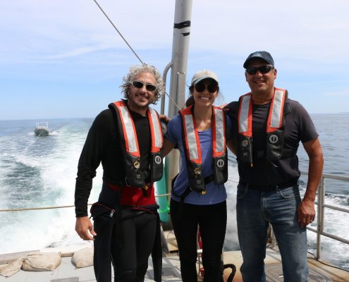 Underwater photographer Keith Ellenbogen stands on the back of a boat with a Knauss Fellow and the superintendent of Stellwagen Bank.