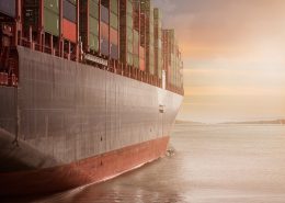 A shipping container on the water at sunset