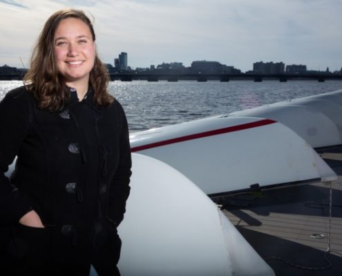 Michelle Kornberg at the MIT Sailing Pavilion dock on the Charles River with a row of sailboats behind