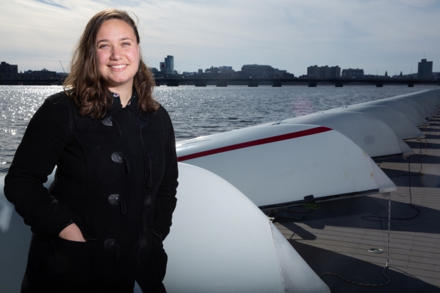 Michelle Kornberg at the MIT Sailing Pavilion dock on the Charles River with a row of sailboats behind