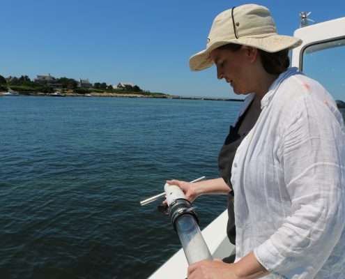 Dr. Juliet Simpson holds sediment core on a boat in Massachusetts.