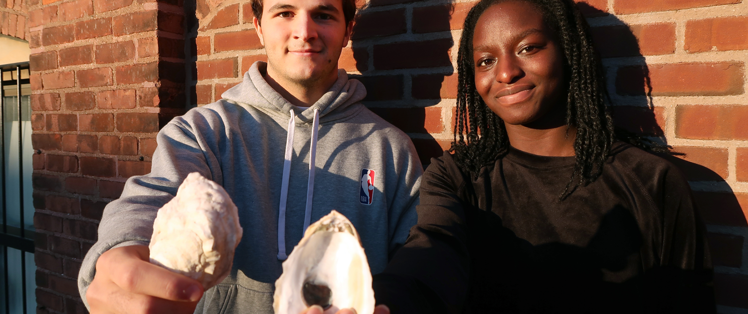 MIT Sea Grant students Santiago Borrego and Unyime Usua hold oyster shells.