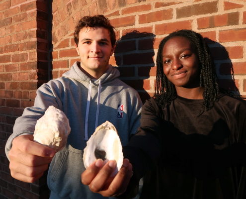 MIT Sea Grant students Santiago Borrego and Unyime Usua hold oyster shells.